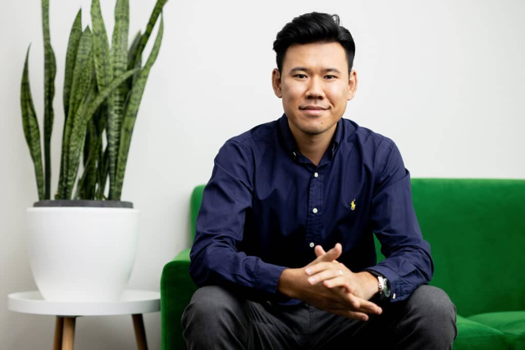 environmental portraits man sitting on green sofa with green plant