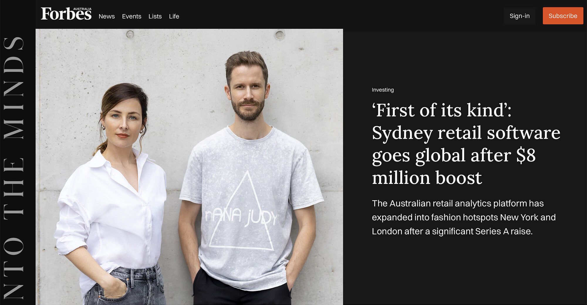 Man and woman in fashion poses standing in front of concrete wall